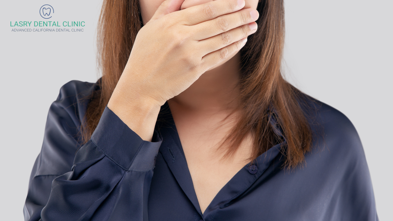 what causes bad breath even after brushing? woman holding hand to mouth